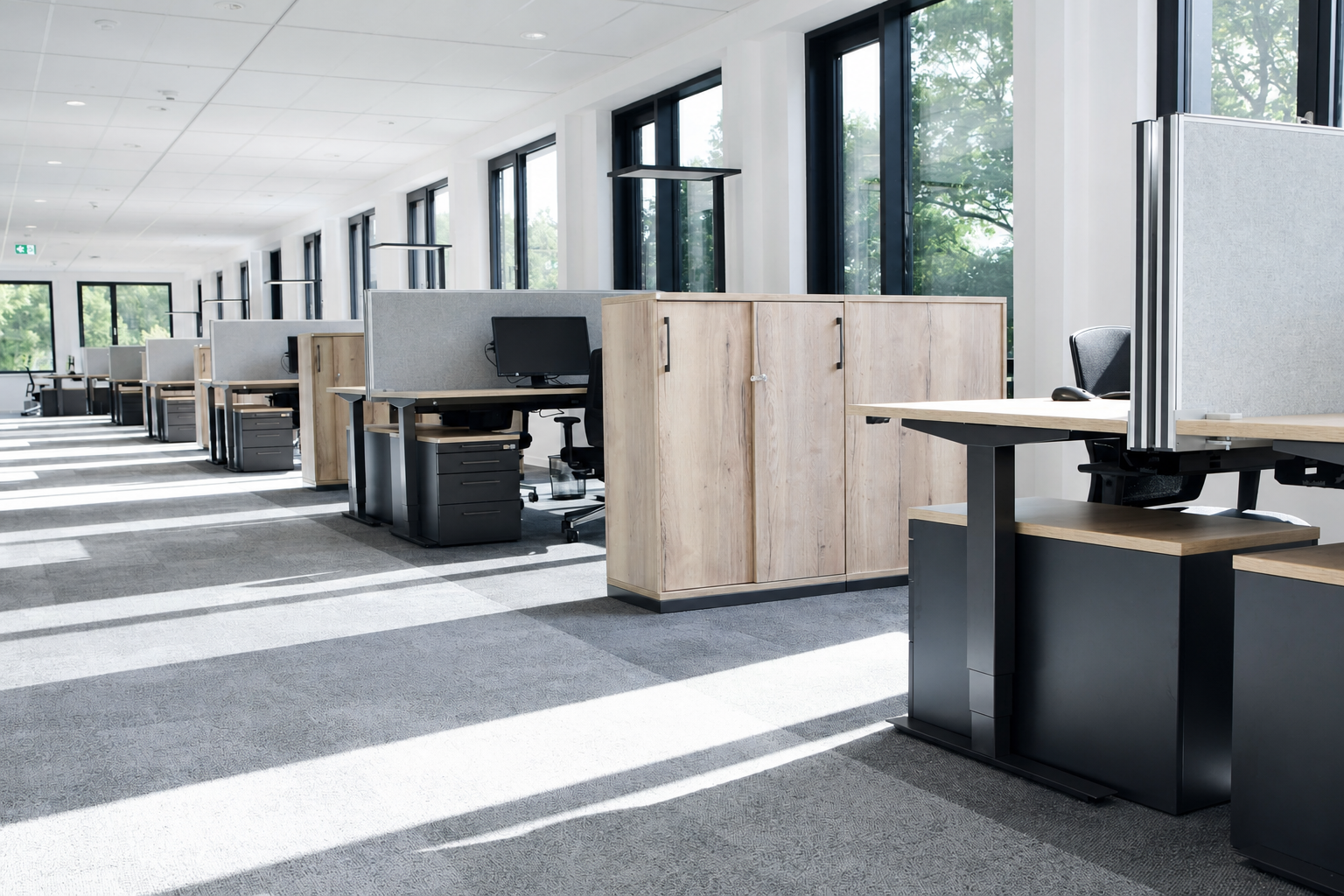 Offener Arbeitsbereich mit Holztischen, schwarzen Stühlen und Tageslicht
